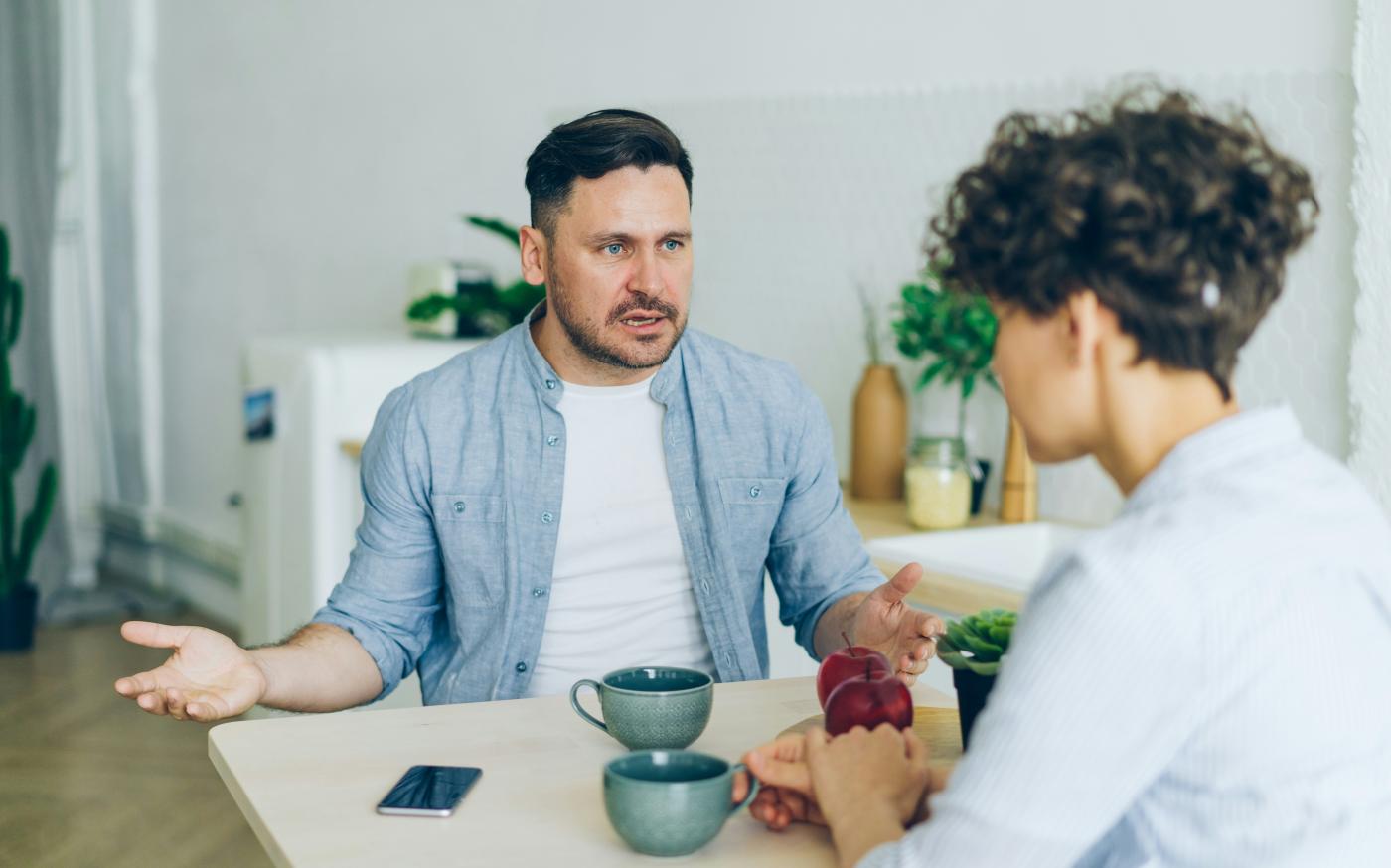 a man sitting at a table talking to a woman by Vitaly Gariev courtesy of Unsplash.