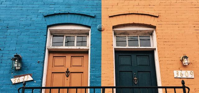 a blue building with a black door by Meg Jenson courtesy of Unsplash.