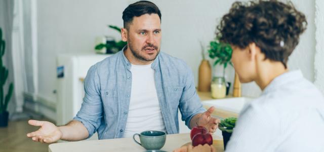 a man sitting at a table talking to a woman by Vitaly Gariev courtesy of Unsplash.